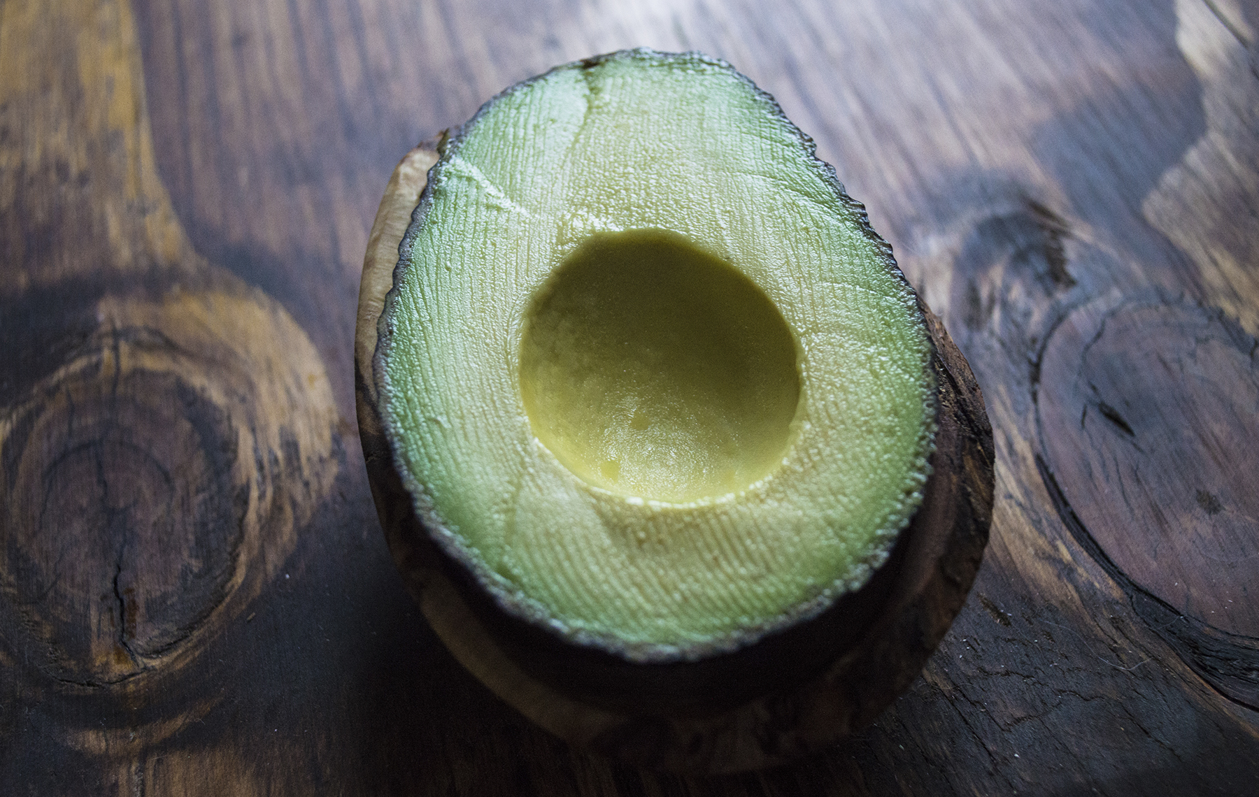 AltaMed half avocado on wooden table